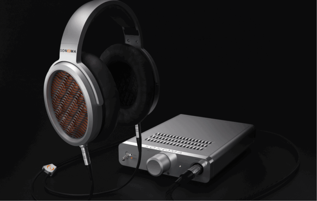 Close-up of over-ear Sonoma headphones connected to a sleek silver desktop headphone amplifier on a black background.