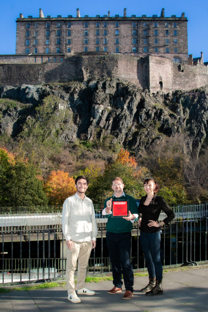 Three Xi team members standing underneath Edinburgh Castle